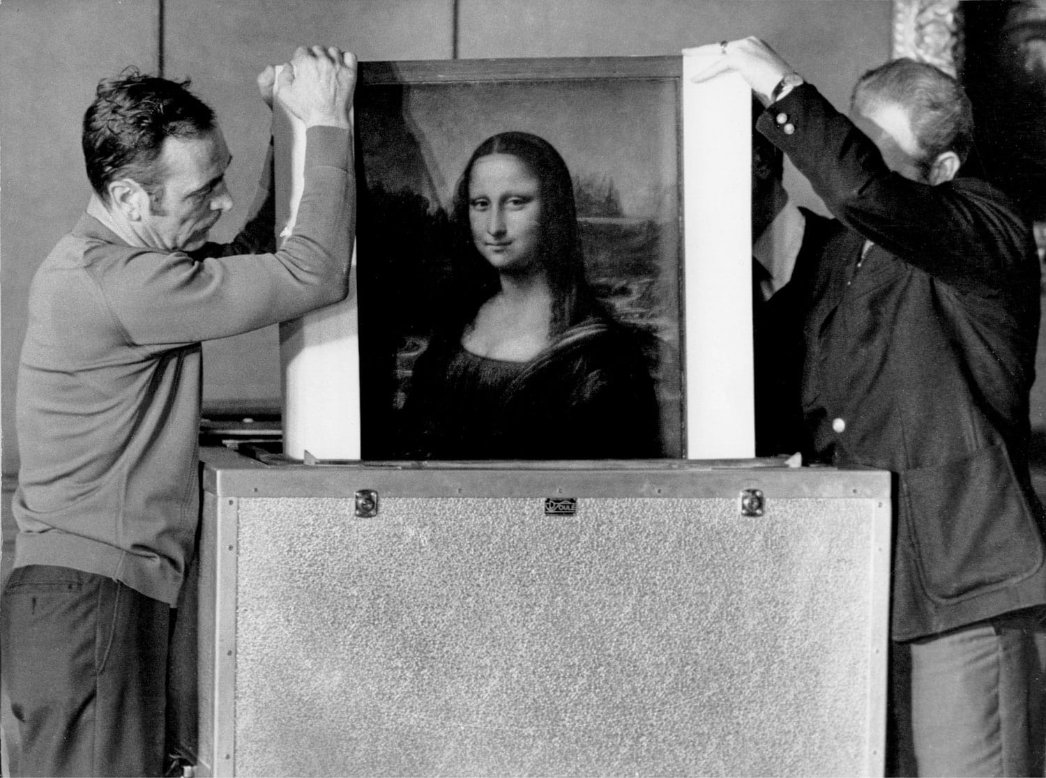 Two people carefully handling and packing the Mona Lisa painting in a protective case.