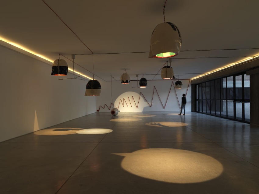Modern art gallery interior with unique dome-shaped lights, minimalist design, and a person observing the artwork.