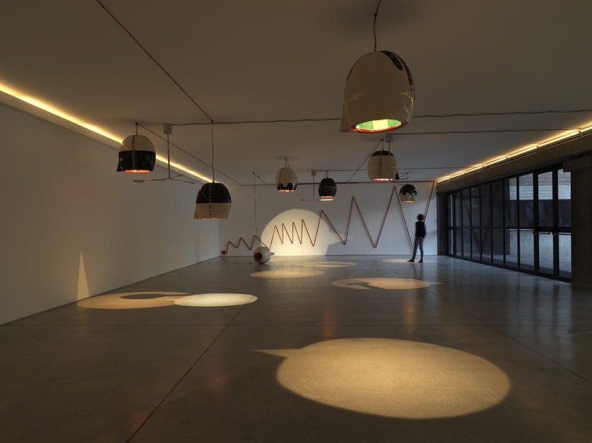 Modern art gallery interior with unique dome-shaped lights, minimalist design, and a person observing the artwork.