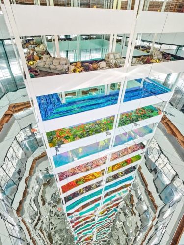 Colorful vertical garden installations in a modern atrium with mirrored walls and natural lighting.