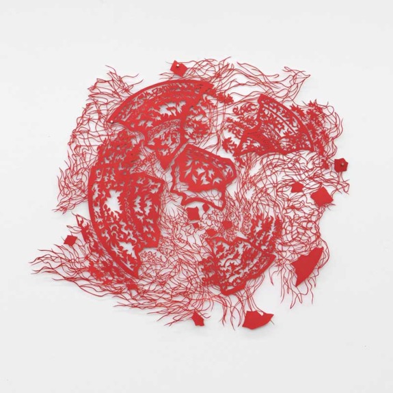 Intricate red paper cutout artwork depicting abstract shapes and patterns on a white background.