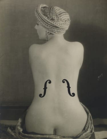 Woman with turban and back tattoos seated, showcasing artistic design and elegance in a vintage black and white photograph.