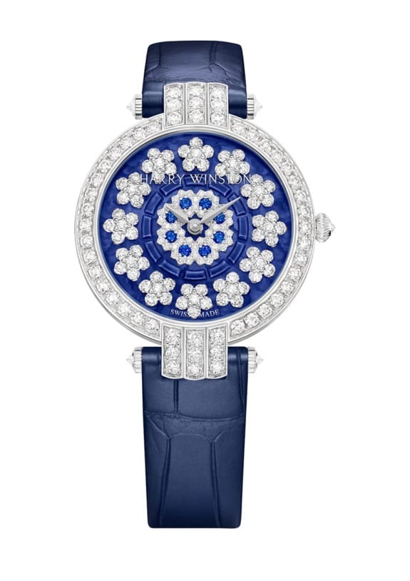 Luxury watch with blue leather strap, diamond-encrusted face, and floral design on the dial.