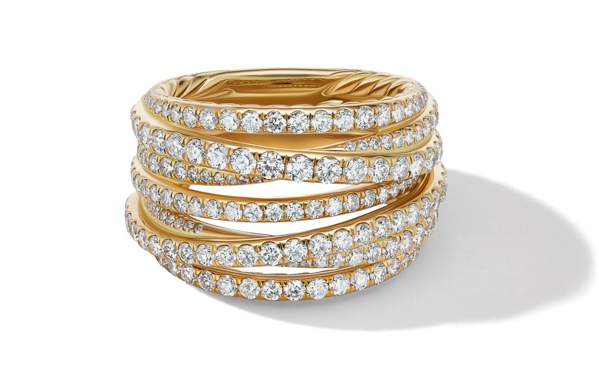 Elegant gold ring with multiple rows of sparkling diamonds wrapped around in a spiral design, casting a soft shadow.