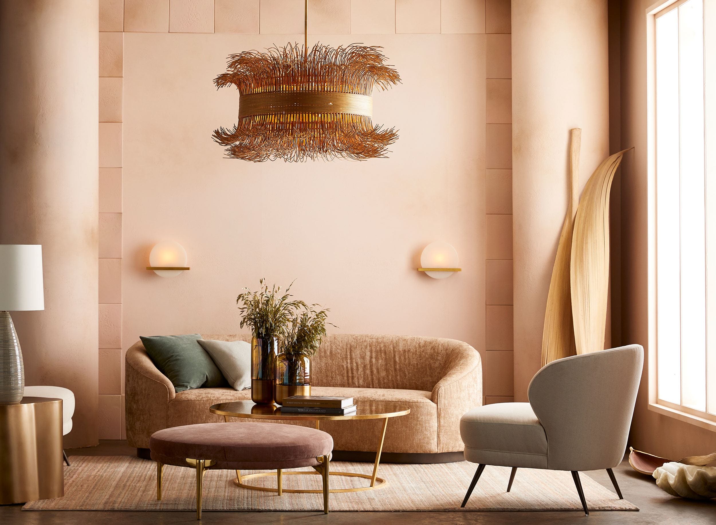 Elegant living room with a modern chandelier, beige sofa, armchair, round coffee table, and decorative surfboard on wall.