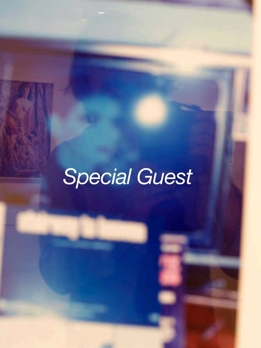 Blurred reflection of a person in a window with the words "Special Guest" overlayed in white text.