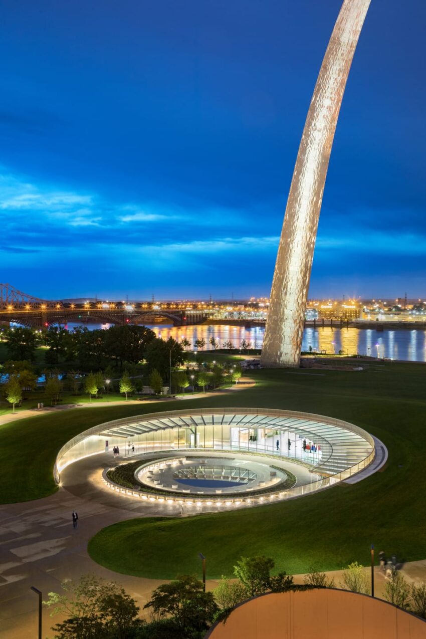 Stunning view of Gateway Arch with illuminated museum entrance at night, reflecting on the water in St. Louis, Missouri.