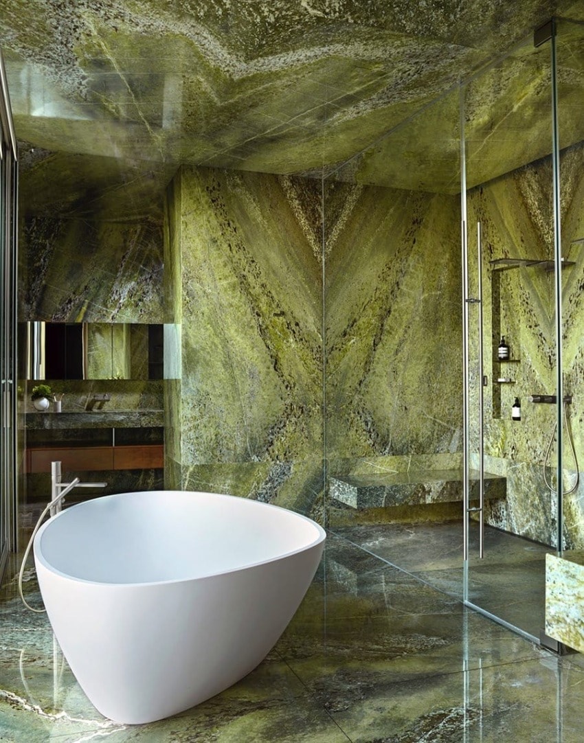 Luxurious marble bathroom with a white freestanding tub and glass shower enclosure.