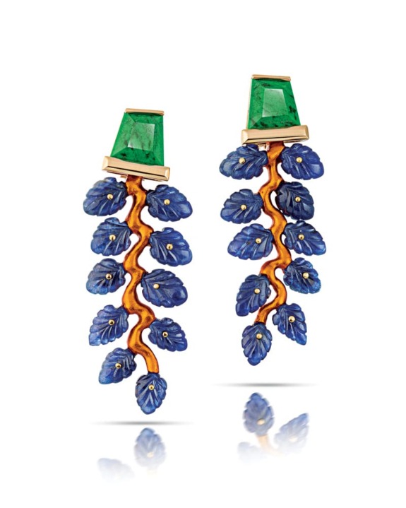 Colorful gemstone earrings with blue leaves and green tops against a white background.