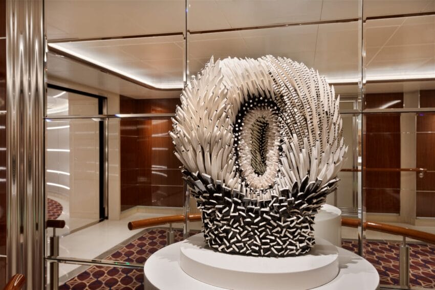 Sculpture with intricate white and black spikes displayed in a modern room with wooden accents and mirrored walls.