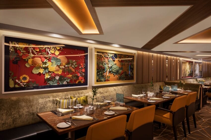Cozy restaurant interior with decorative wall art, plush seating, and tables set for dining. Warm lighting creates an inviting ambiance.