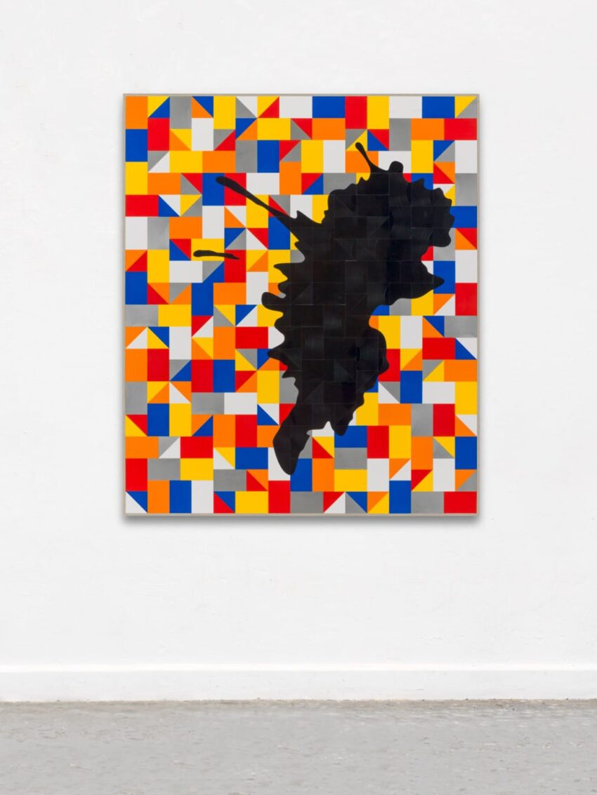 Abstract art with colorful geometric patterns and a central irregular black shape on a wall.