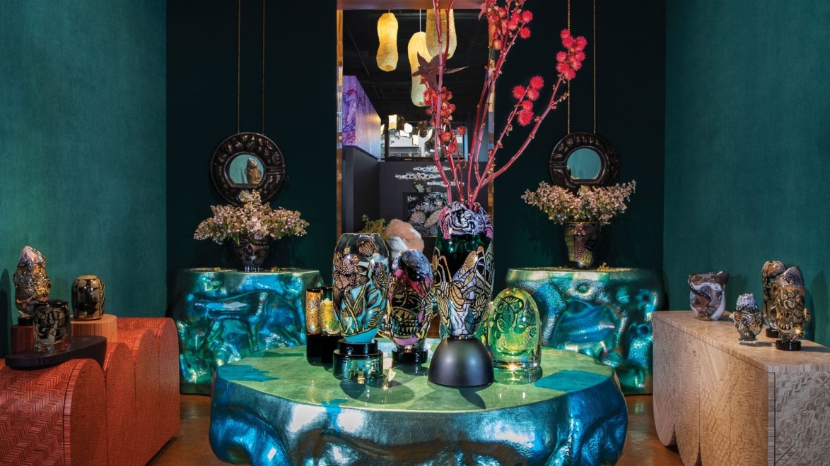 Luxurious showroom with ornate vases on artistic tables, colorful flowers, and vibrant decor pieces in a richly lit setting
