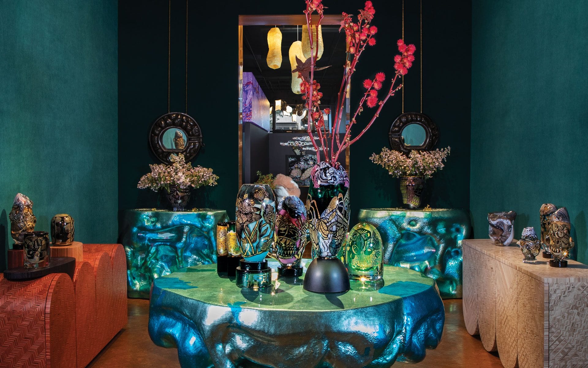 Luxurious showroom with ornate vases on artistic tables, colorful flowers, and vibrant decor pieces in a richly lit setting