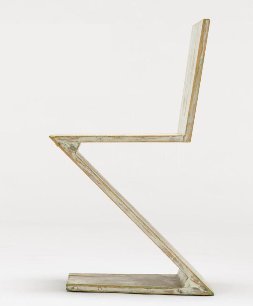 Side view of a Z-shaped modern chair with a minimalist design and a light-colored wooden finish.
