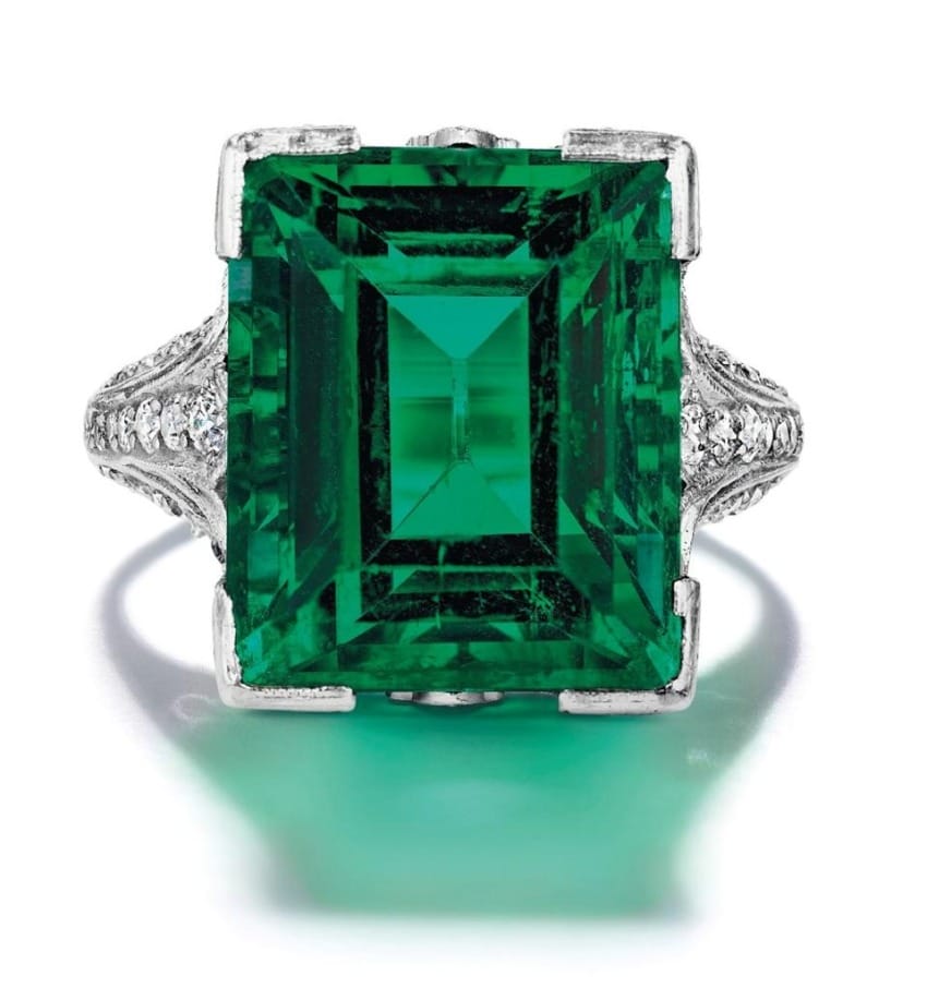 Emerald-cut green gemstone ring with intricate silver band design.