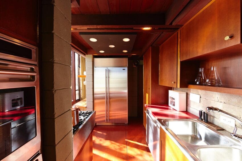 Modern kitchen with stainless steel appliances, wooden cabinets, and sunlight streaming through a window.