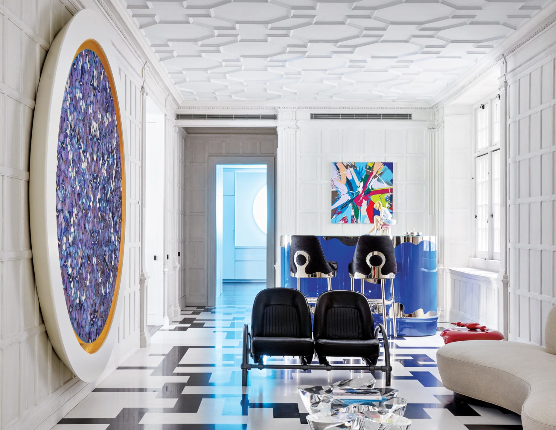 Modern art-filled room with large circular painting, abstract art, sleek black and white flooring, and contemporary furniture.