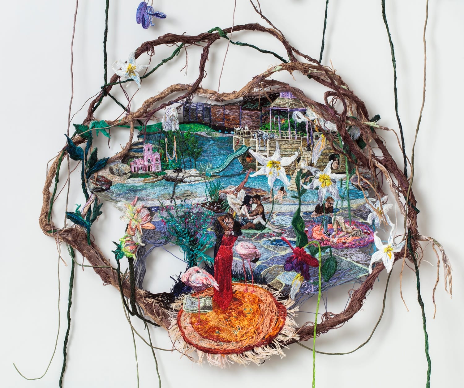 Circular embroidery art featuring a vibrant landscape with figures, flowers, and intricate details, framed by natural vines.