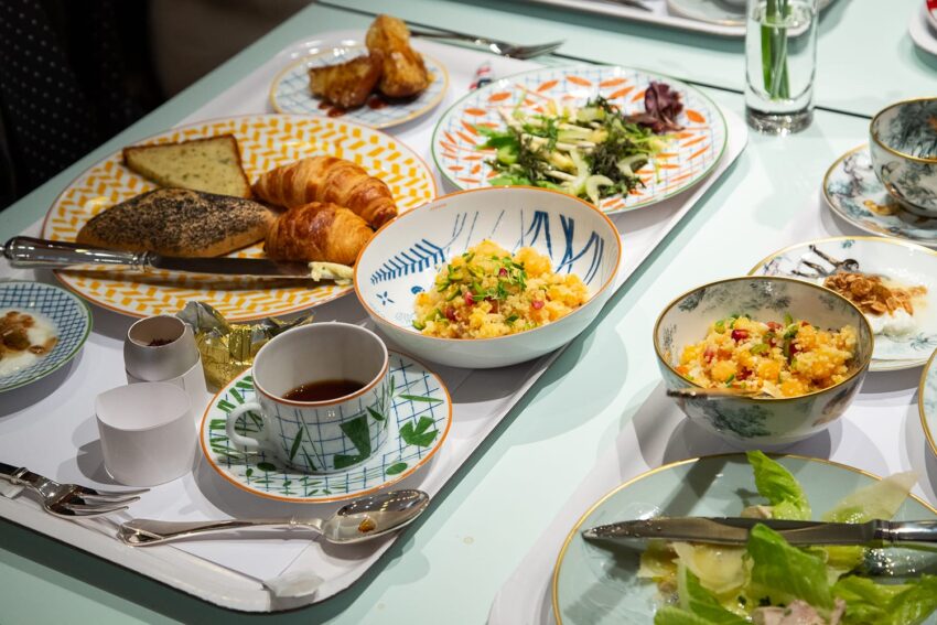 Assorted breakfast foods including pastries, salad, and tea on a table with patterned dishes and cutlery.