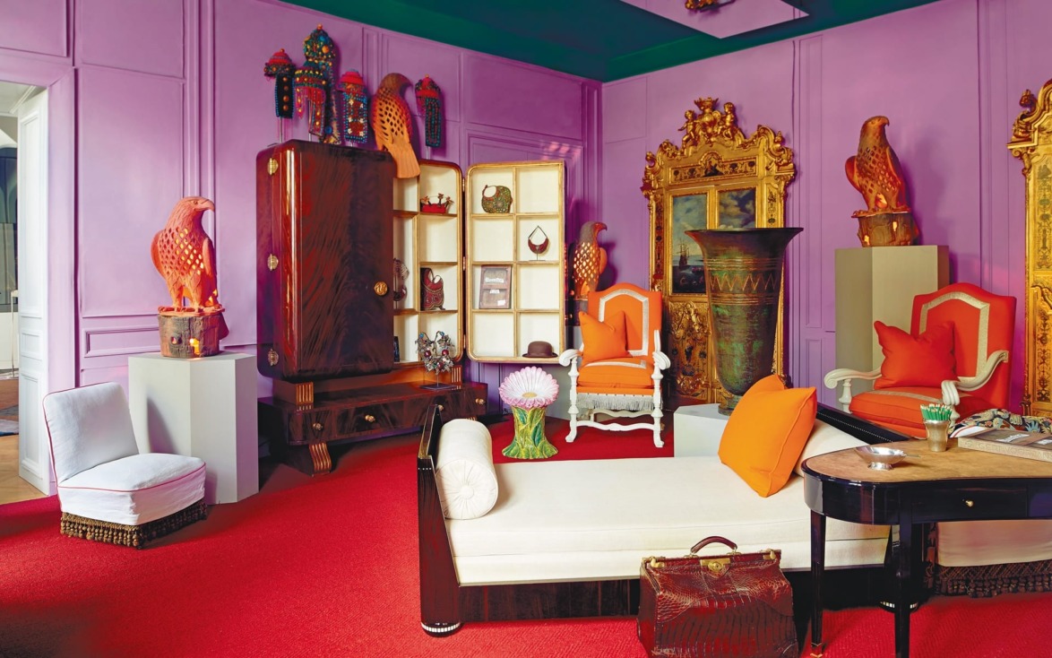 A colorful room with purple walls, red carpet, eclectic furniture, and vibrant decor pieces.
