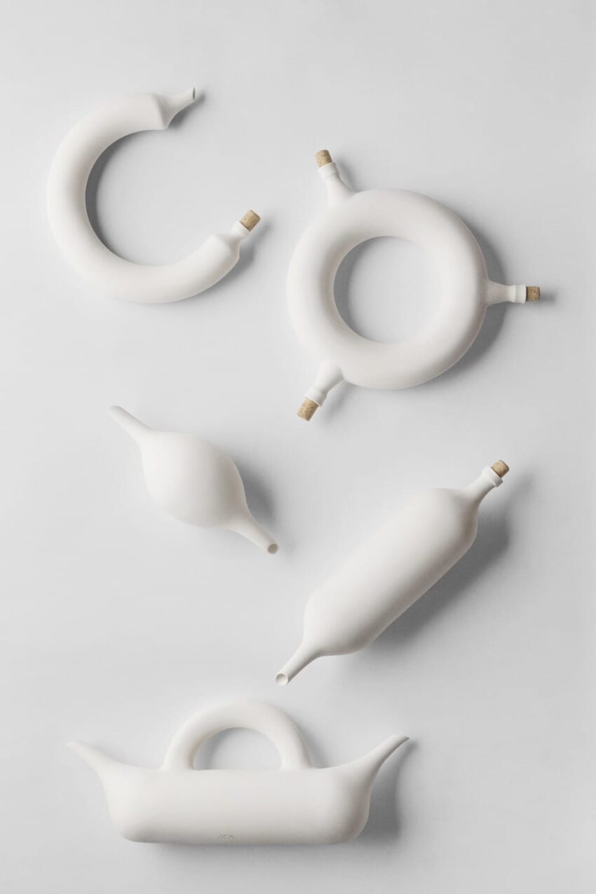 Abstract white ceramic shapes with cork stoppers arranged on a light background.