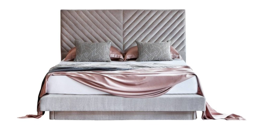 Modern bed with a gray quilted headboard, stylish pillows, and a draped satin sheet in a cozy bedroom setting