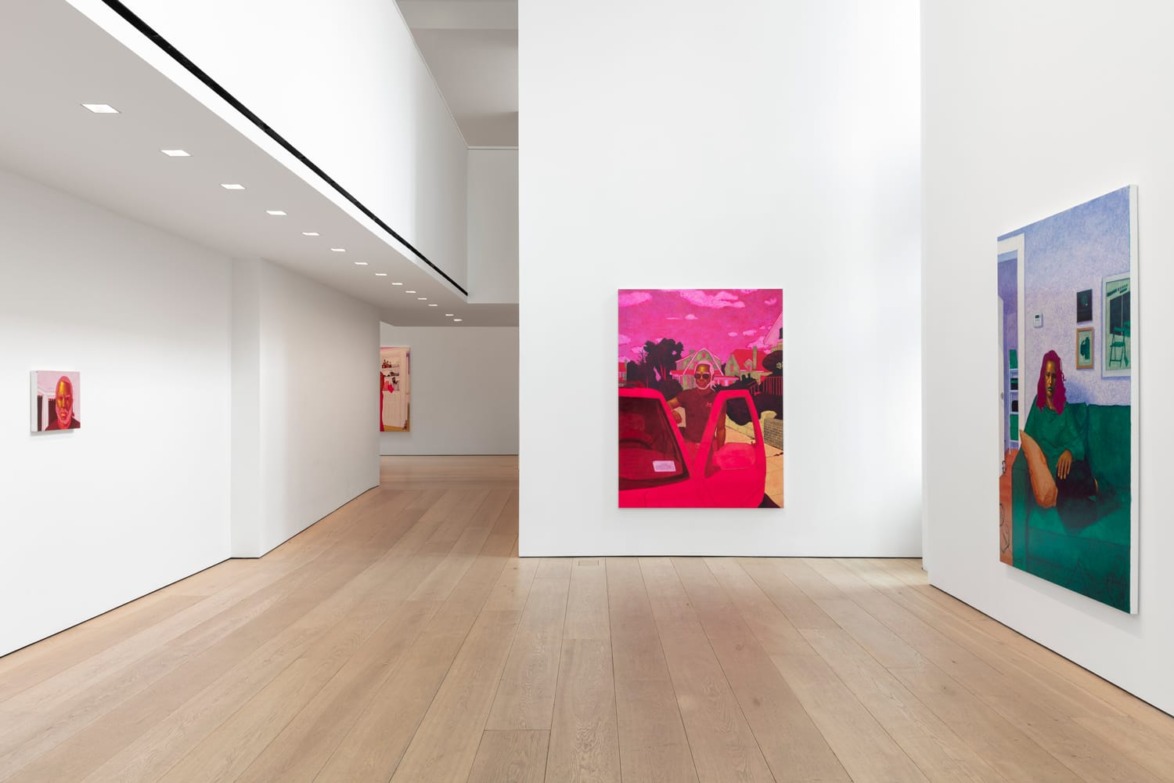 Gallery interior with colorful modern art paintings on white walls and a wooden floor.