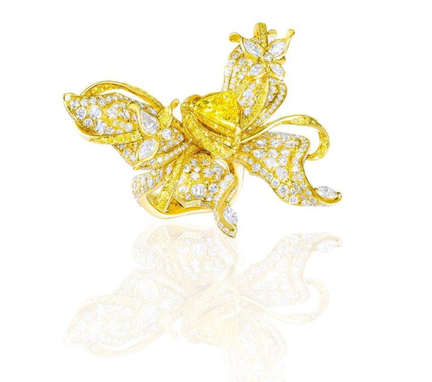 Intricate gold butterfly-shaped jewelry piece adorned with sparkling diamonds on a reflective surface.