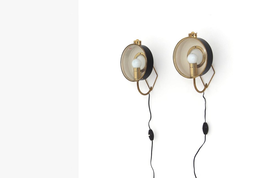 Pair of vintage wall-mounted brass lamps with exposed bulbs and black cords against a white background.
