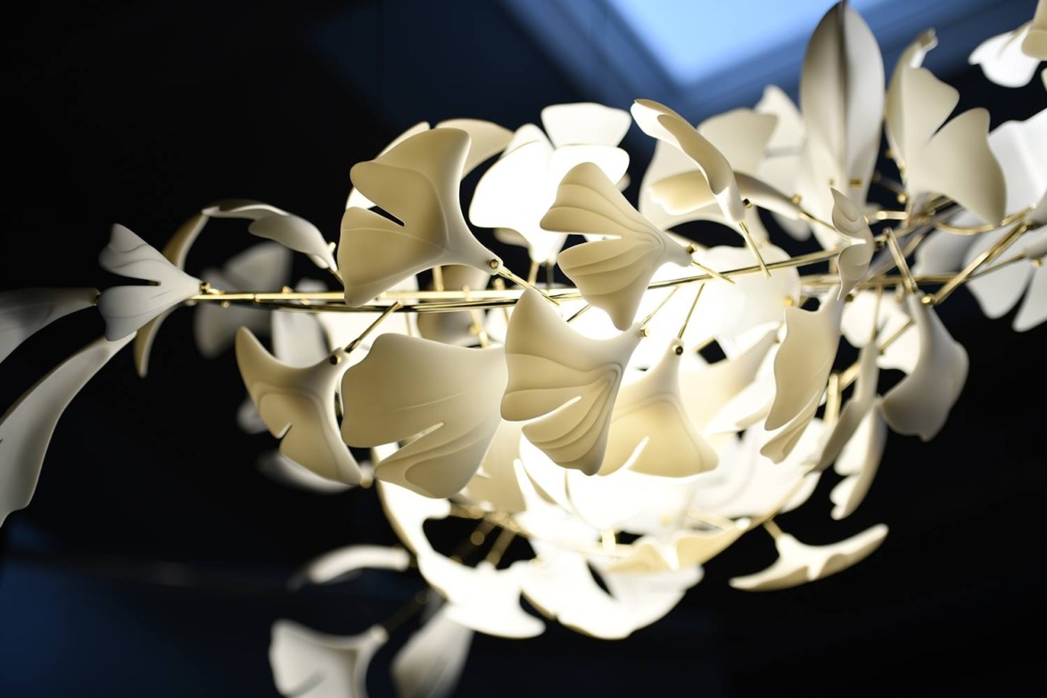 Contemporary white pendant light fixture with leaf-like design elements, illuminated against a dark background.