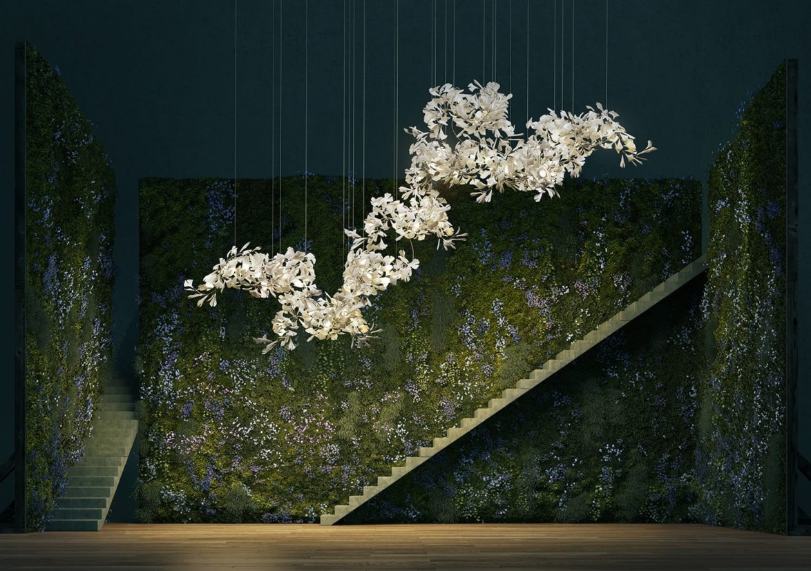 Elegant modern chandelier with floral design hanging in a green, plant-covered room with two staircases.