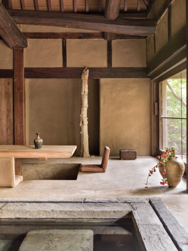Traditional Japanese interior with wooden beams, tatami mat, rustic decor, and a large window showing greenery outside.