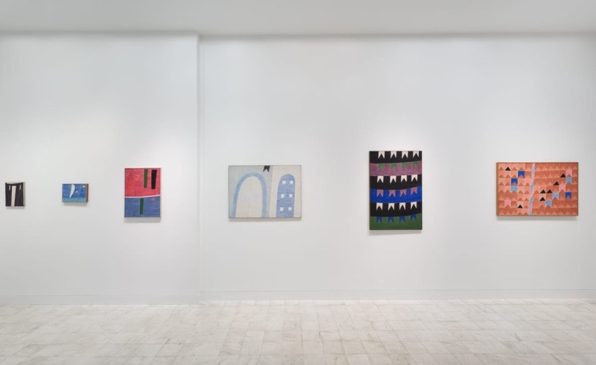 Art gallery wall displaying abstract paintings in various sizes and colors on a white background.