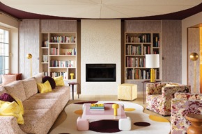 Textured plasterwork animates the ceiling and fireplace surround in the living area, which is anchored by a Liaigre sofa covered in a Métaphores fabric. Pailleret designed the gold floor lamps and the organic-shaped rug made by Codimat Collection.