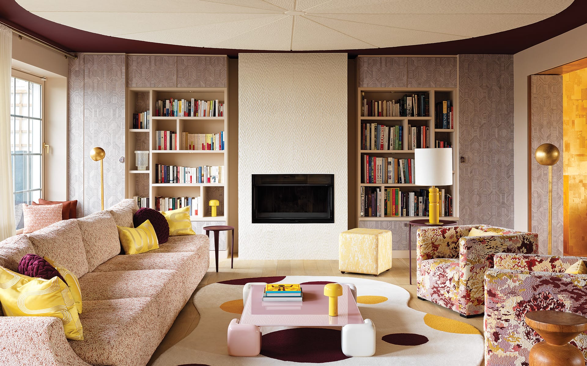 Textured plasterwork animates the ceiling and fireplace surround in the living area, which is anchored by a Liaigre sofa covered in a Métaphores fabric. Pailleret designed the gold floor lamps and the organic-shaped rug made by Codimat Collection.