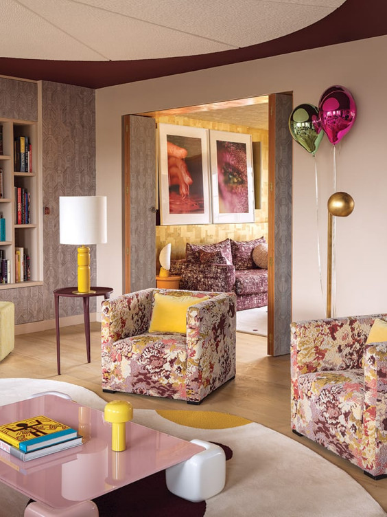 A Jeppe Hein balloon sculpture helps set a spirited tone in the living area of a Paris apartment by designer Anne-Sophie Pailleret, who installed Liaigre armchairs clad in a vibrant Métaphores fabric facing a custom cocktail table with a glass top in a candy pink. An Arte paper accents one wall as well as the folding doors, which open to the family room, where photographs by Marilyn Minter are mounted atop a Phillip Jeffries wall covering.