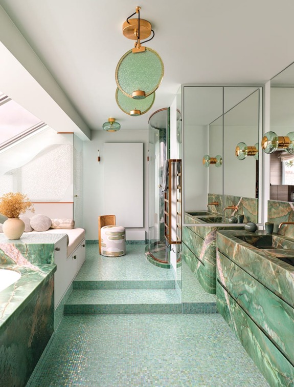 In the primary bath, which features a floor of Sicis mosaic tiles, Pierre Gonalons pendants hang above an emerald quartzite tub and vanity.