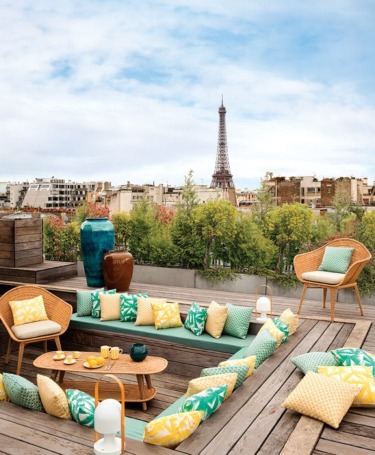 Outfitted with wicker furnishings and vases by CFOC, the rooftop terrace is enlivened by cushions and pillows in an array of Dedar fabrics.