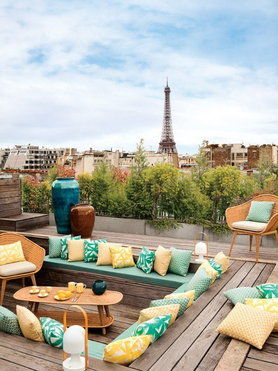 Outfitted with wicker furnishings and vases by CFOC, the rooftop terrace is enlivened by cushions and pillows in an array of Dedar fabrics.