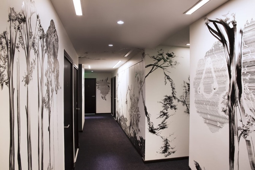 hallway with artistic black and white wall designs, recessed lighting, and dark doors