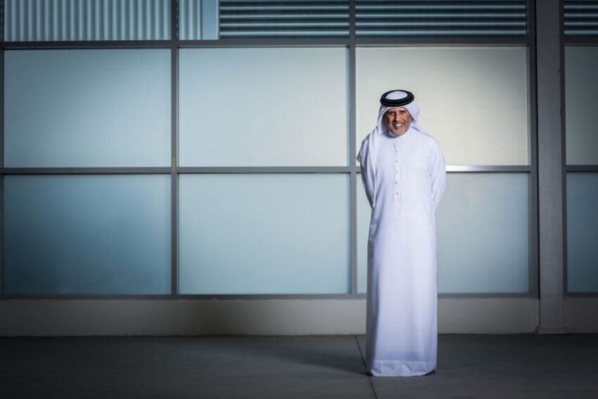 Person wearing traditional Middle Eastern attire stands in front of a large window.