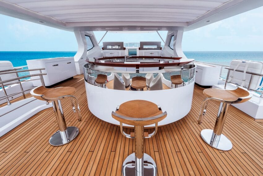 Luxury yacht deck with wooden bar stools, sleek bar, and ocean view. Ideal for relaxation and enjoying the sea.