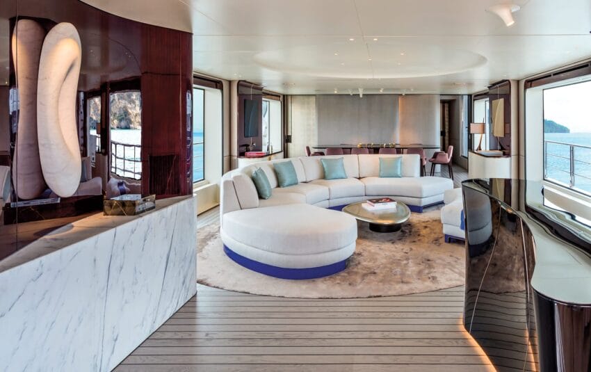 Luxurious yacht interior with modern circular seating, panoramic windows, and elegant decor overlooking the ocean.