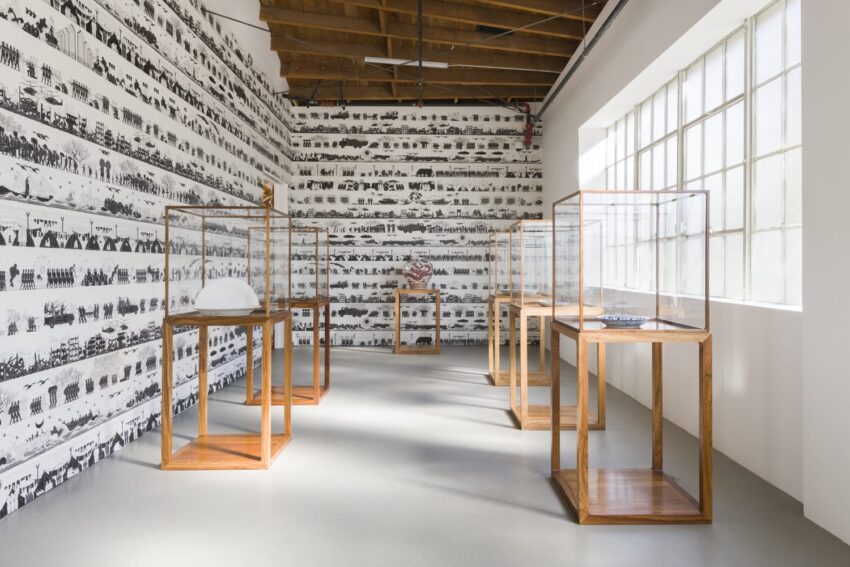 Art gallery interior with wooden display cases and historical black and white photos covering the walls.