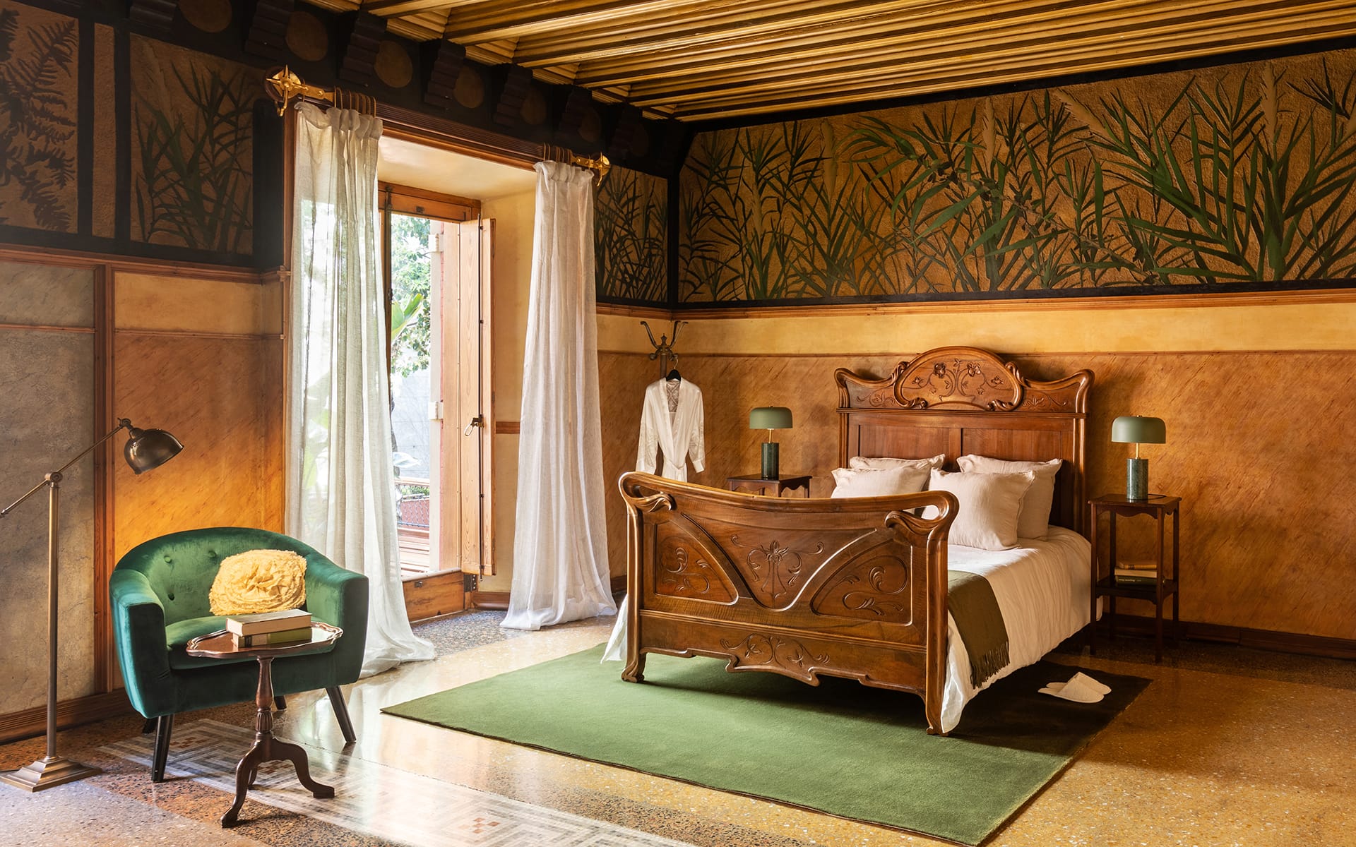 Elegant bedroom with wooden bed, green chair, and large window with flowing curtains, featuring nature-themed decor.
