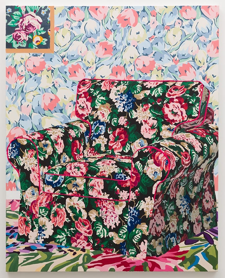 Floral-patterned armchair in front of matching wallpaper and rug with vibrant, colorful flowers.