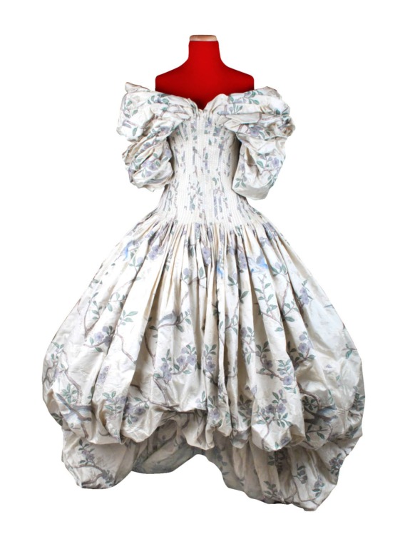 Vintage white floral dress with puffed sleeves and voluminous skirt displayed on a red mannequin.