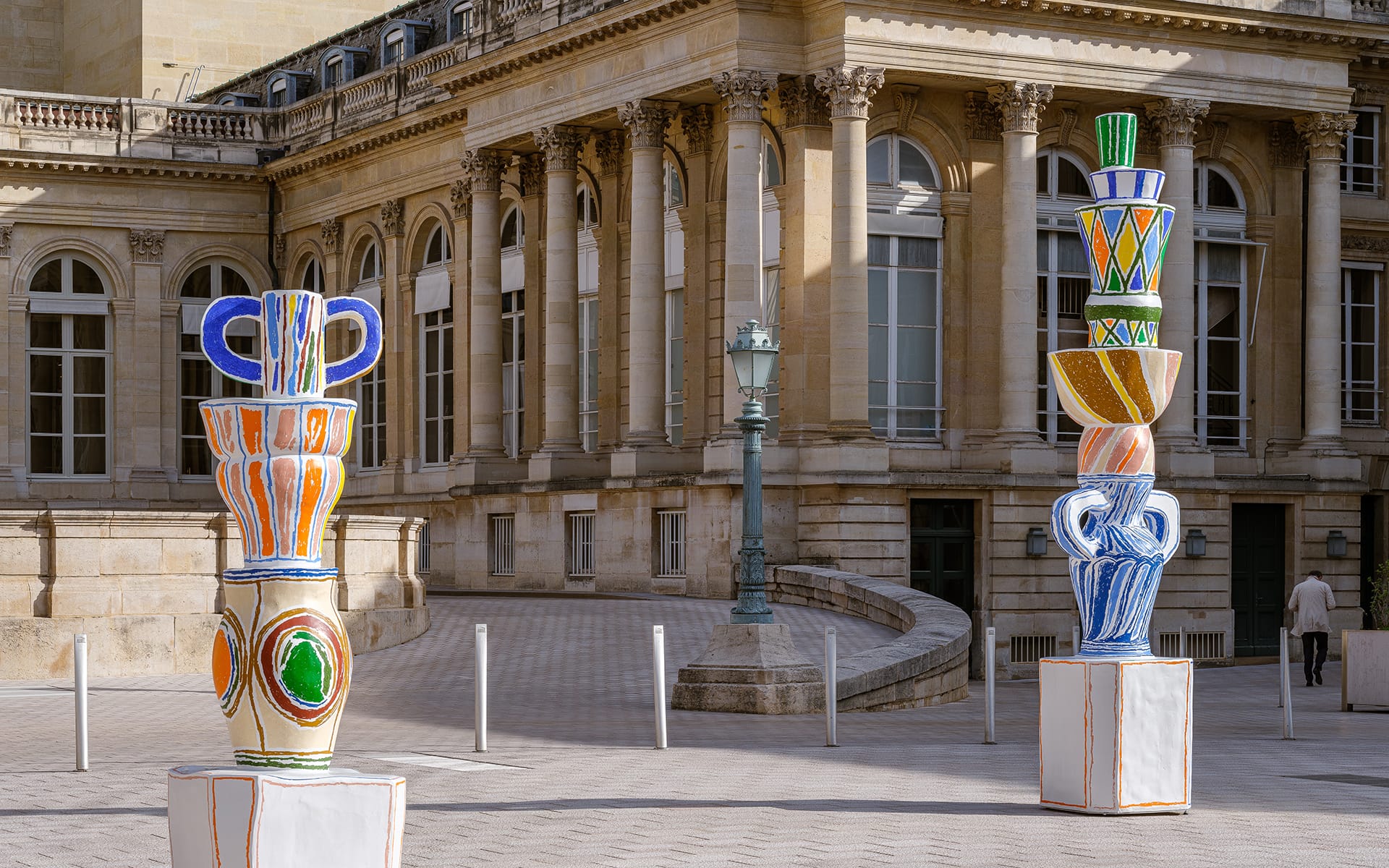 Colorful ceramic sculptures displayed outdoors in front of a historic building with tall windows and ornate details.