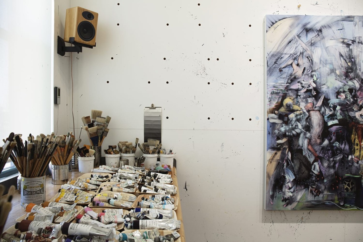 Artist's studio with painting supplies on a table and an abstract painting on the wall.